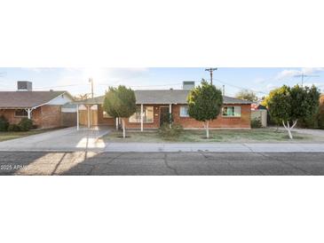 Charming single-story brick home featuring a covered carport, mature landscaping, and a well-maintained front yard at 6808 N 33Rd Ave, Phoenix, AZ 85017