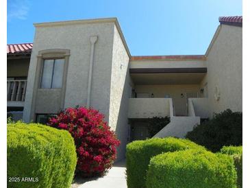 Charming condo featuring well-maintained landscaping, flowering bushes, and classic architecture at 8649 E Royal Palm Rd # 213, Scottsdale, AZ 85258