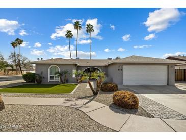 Charming single-story home featuring a desert landscape, palm trees, a two-car garage, and an arched entryway at 2256 S Noche De Paz --, Mesa, AZ 85202