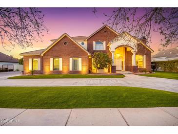 Brick home featuring arched entrance, manicured lawn, and circular driveway at 2458 E Melrose St, Mesa, AZ 85213