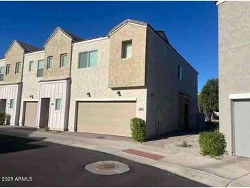 Modern townhouse with a two-car garage and landscaped front, under a clear blue sky at 8330 N 22Nd Ln, Phoenix, AZ 85021