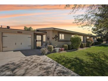 Charming single story home with attached garage, mature landscaping, and a cozy front entry under a colorful sky at 11011 N Coggins Dr, Sun City, AZ 85351