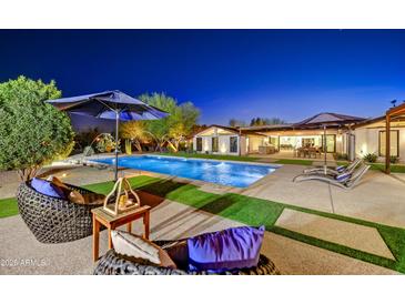Backyard pool and patio area with comfortable seating and manicured landscaping at dusk at 11801 N Sundown Dr, Scottsdale, AZ 85260