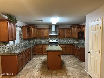 Spacious kitchen with dark wood cabinets, a center island, and stainless steel appliances at 12733 W Boca Raton Rd, El Mirage, AZ 85335