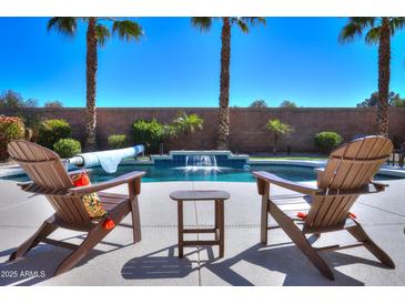 Inviting backyard pool area with waterfall feature and comfortable lounge chairs, perfect for relaxing and entertaining outdoors at 21857 N Gibson Dr, Maricopa, AZ 85139