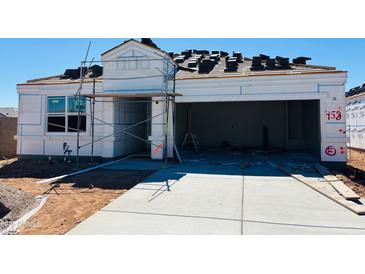 New construction home featuring open garage, paved driveway, and roof tiles ready for installation at 28200 N Nealite Dr, San Tan Valley, AZ 85143