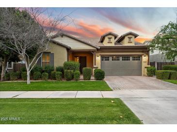 Charming single-story home with a well-manicured lawn and a two-car garage under a sunset sky at 4088 E Comstock Dr, Gilbert, AZ 85296