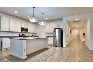 Bright, white kitchen featuring stainless steel appliances, a center island, and wood-look tile flooring at 559 W Magena Dr, San Tan Valley, AZ 85140