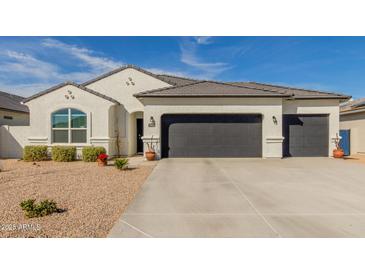 Beautiful single-story home showcasing a three car garage and neutral desert landscaping at 9404 E Grapefruit Dr, Florence, AZ 85132