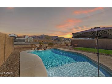 Beautiful backyard pool featuring a waterfall feature and umbrella with sunset views at 12686 E Pivot Peak --, Gold Canyon, AZ 85118