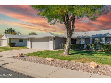 Charming single-story home with a well-maintained lawn, tree, and two-car garage at 12706 W Shadow Hills Dr, Sun City West, AZ 85375