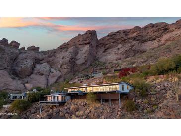 Stunning exterior shot of a modern home built into the side of a mountain at 4959 E Red Rock Dr, Phoenix, AZ 85018