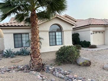 Charming single-story home featuring desert landscaping, palm tree and a two-car garage at 9033 E Pine Valley Rd, Scottsdale, AZ 85260