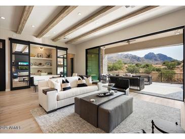 Bright living room featuring wood beam ceiling, modern furnishings, and seamless indoor/outdoor flow to a patio with mountain views at 12315 E Black Rock Rd, Scottsdale, AZ 85255