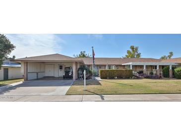 Charming single-story home featuring a covered carport, well-manicured lawn, and traditional design elements at 13410 N Cedar Dr, Sun City, AZ 85351