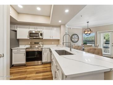Modern kitchen featuring white cabinets, stainless steel appliances, and a spacious countertop island at 15095 N Thompson Peak Pkwy # 1053, Scottsdale, AZ 85260