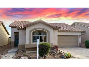 Inviting single-story home with a neutral-toned exterior, well-kept yard and tile roof, under a vibrant sunset sky at 9537 E Flint Dr, Gold Canyon, AZ 85118