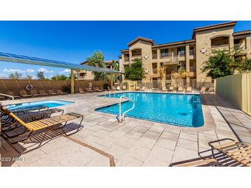 Community swimming pool and hot tub area with lounge chairs and clear blue skies at 10136 E Southern Ave # 3065, Mesa, AZ 85209