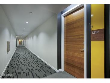 Modern condo hallway with geometric carpeting, light walls, and stained wood door with unit number at 200 W Portland St # 1217, Phoenix, AZ 85003