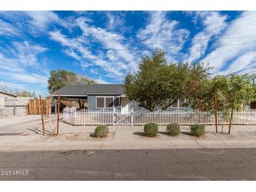 Charming home features a white picket fence, lovely landscaping, and a welcoming entrance, perfect for curb appeal at 7313 N 55Th Dr, Glendale, AZ 85301