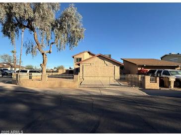 Beige two-story home with a desert landscaped front yard and gated entry at 8154 W Greer Ave, Peoria, AZ 85345