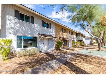 Charming townhome featuring a painted brick facade, a covered entryway, and well-maintained landscaping at 1575 W Hazelwood St, Phoenix, AZ 85015