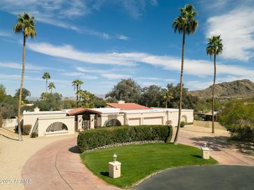 Stunning desert home with a circular driveway, mature palm trees, and elegant architecture at 4744 E Desert Park Pl, Paradise Valley, AZ 85253