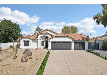 Charming single-story home with a desert landscape, barrel tile roof, and three-car garage at 5704 E Estrid Ave, Scottsdale, AZ 85254