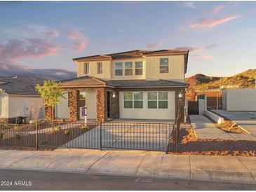 Beautiful two-story home with stone accents, modern design, and well-maintained landscaping with wrought iron front gate at 7441 W Buckhorn Trl, Peoria, AZ 85383