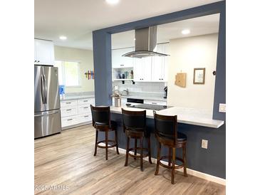 Bright kitchen features white cabinets, stainless appliances, and an island with bar stool seating at 12543 W Brandywine W Dr, Sun City West, AZ 85375