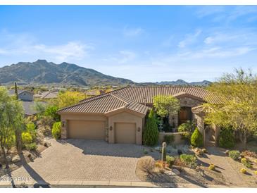 Stunning exterior view of a Southwestern-style home with a tile roof, three car garage, and desert landscaping at 37170 N Granite Creek Ln, Carefree, AZ 85377
