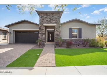 Charming single-story home featuring a stone accented entrance, manicured lawn and attached two car garage at 4683 N 206Th Ln, Buckeye, AZ 85396