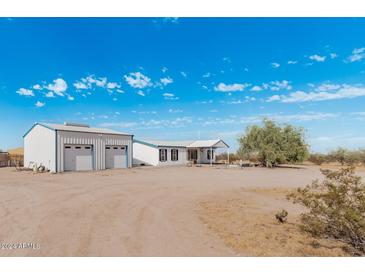 Wide exterior view of a home and detached garage in a desert environment at 53040 W Whirly Bird Rd, Maricopa, AZ 85139