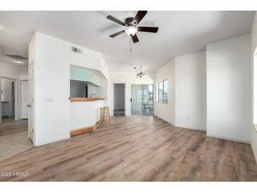 Bright living room featuring wood floors, a ceiling fan, and access to a balcony with natural light at 7101 W Beardsley Rd # 722, Glendale, AZ 85308