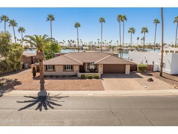 Charming waterfront home featuring desert landscaping, brick driveway and plentiful palm trees at 9945 W Cameo Dr, Sun City, AZ 85351