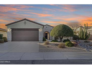 Charming single-story home featuring a stone-accented facade, a desert landscape, and a two-car garage at 20044 N London Bridge Dr, Surprise, AZ 85387