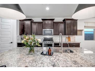 Stylish kitchen with a large granite island, stainless steel appliances and dark cabinetry at 3010 W Laredo Ln, Phoenix, AZ 85085
