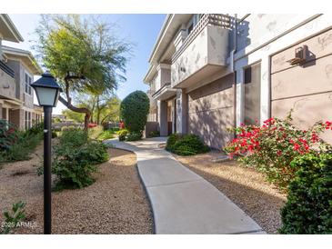 Inviting two-story condo with a landscaped walkway, a light post, and colorful flowers at 15221 N Clubgate Dr # 2012, Scottsdale, AZ 85254