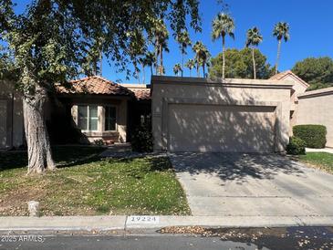 Charming home featuring a 2-car garage, desert landscaping, and beautiful palm trees against a clear blue sky at 19224 N 93Rd Ave, Peoria, AZ 85382
