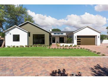 Inviting single-story home with manicured lawn, brick driveway, and a modern two-car garage at 220 E Georgia Ave, Phoenix, AZ 85012