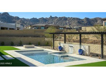 Stunning pool with travertine tile and mountain views create a luxurious outdoor oasis at 23964 N 128Th Pl, Scottsdale, AZ 85255