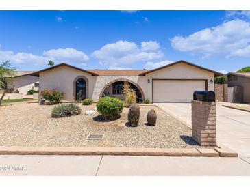 Tan single story home featuring a xeriscaped front yard, archway entry and two car garage at 4828 E Capistrano Ave, Phoenix, AZ 85044