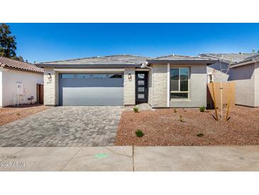 Charming single-story home featuring a gray stone facade and a well-manicured front yard with paver driveway at 5358 W Las Palmaritas Dr, Glendale, AZ 85302
