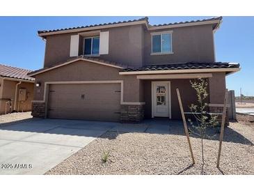 Two-story home featuring a two-car garage, a covered porch, and low-maintenance gravel landscaping at 1057 W West Virginia Ave, Florence, AZ 85132