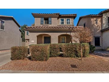 Charming two-story home featuring a tile roof, arched entryway, and well-maintained landscaping in a residential neighborhood at 10938 W Pierson St, Phoenix, AZ 85037