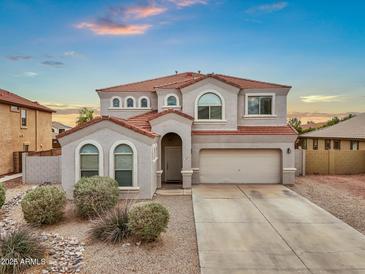 Charming two-story home with a red tile roof, stucco exterior, arched windows, desert landscaping and an attached two-car garage at 647 E Palomino Way, San Tan Valley, AZ 85143