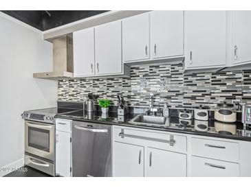 Well-lit kitchen features white cabinetry, stainless steel appliances, and a decorative mosaic backsplash at 4750 N Central Ave # 7D, Phoenix, AZ 85012