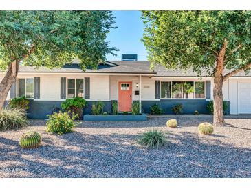 Charming home featuring xeriscape landscaping, mature shade trees, and a vibrant coral colored front door at 3326 N 82Nd Pl, Scottsdale, AZ 85251