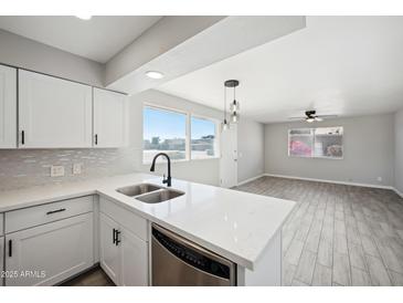 Bright kitchen featuring white cabinets, stainless steel appliances, and a view to the living area at 4737 E Belleview St, Phoenix, AZ 85008