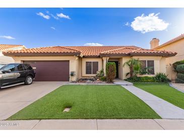 Charming single-story home featuring a red tile roof, green artificial lawn, and desert landscaping at 607 W Palo Verde St, Gilbert, AZ 85233